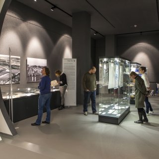 Mehrere Besucherinnen und Besucher betrachten interessiert die Ausstellungsobjekte im Ausstellungsraum Duisburg.