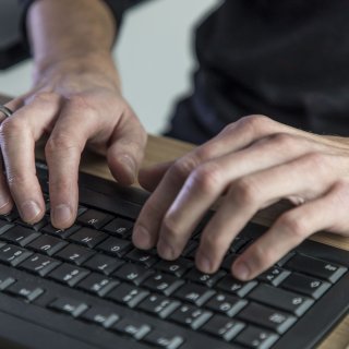 Ein Mann schreibt etwas mit seiner Computertastatur.