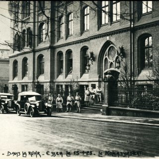 Backsteingebäude mit mehreren Autos davor.