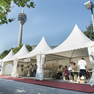 Drei weiße Pavillons im Freien mit Besucherinnen und Besuchern 