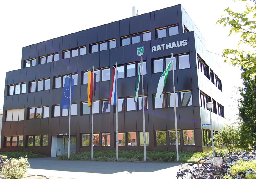 Abbildung des Rathauses in Herzebrock-Clarholz mit wehenden Fahnen im Vordergrund