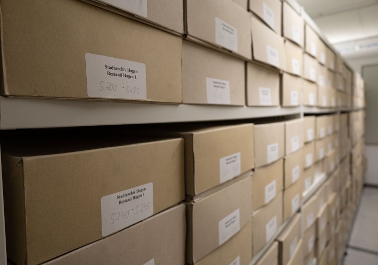 Braune Archivkisten in einem Rollregal Auf den Kisten befindet sich ein weißer Zettel mit der Aufschrift "Stadtarchiv Hagen, Bestand Hagen 1"