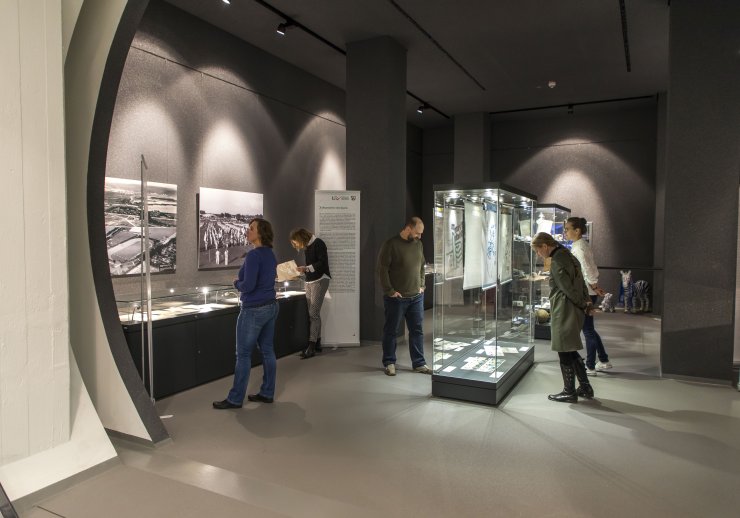 Mehrere Besucherinnen und Besucher betrachten interessiert die Ausstellungsobjekte im Ausstellungsraum Duisburg.