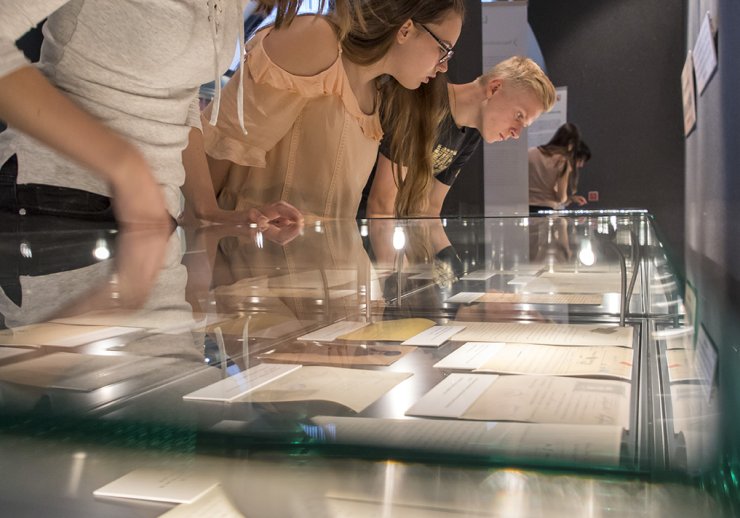 Junge Leute betrachten die Ausstellungsstücke in beleuchteten Schaukästen.