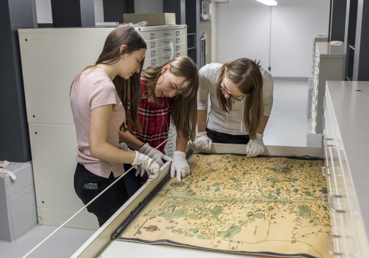 3 Schülerinnen betrachten eine historische Karte 