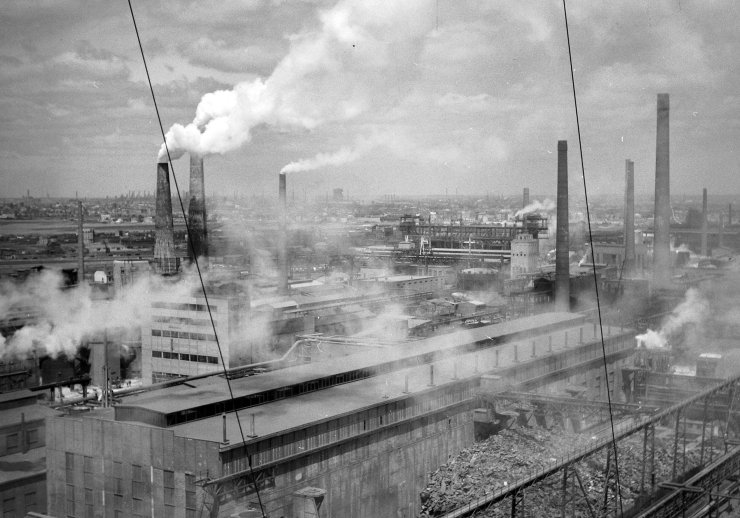 Schwarz weiß Fotografie einer Industrielandschaft mit rauchenden Schornsteinen