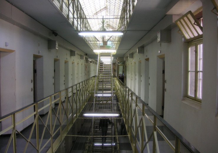 Obere Etage eines Gefängnisses. Rechts und links gehen Gefängniszellen ab, in der Mitte kann man auf die nächsttiefere Ebene schauen.