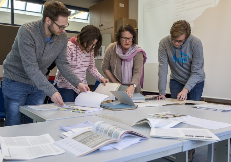 Eine Archivarin erklärt Schülerinnen und Schülern den Umgang mit Archivgut. 